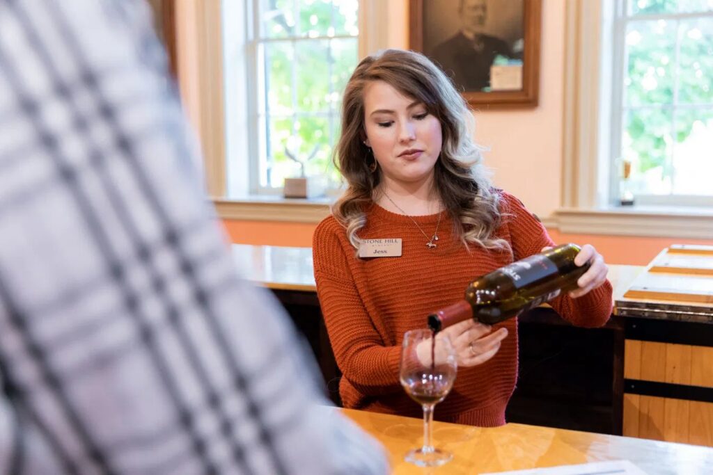 Tasting room host pouring a glass of wine for a guest