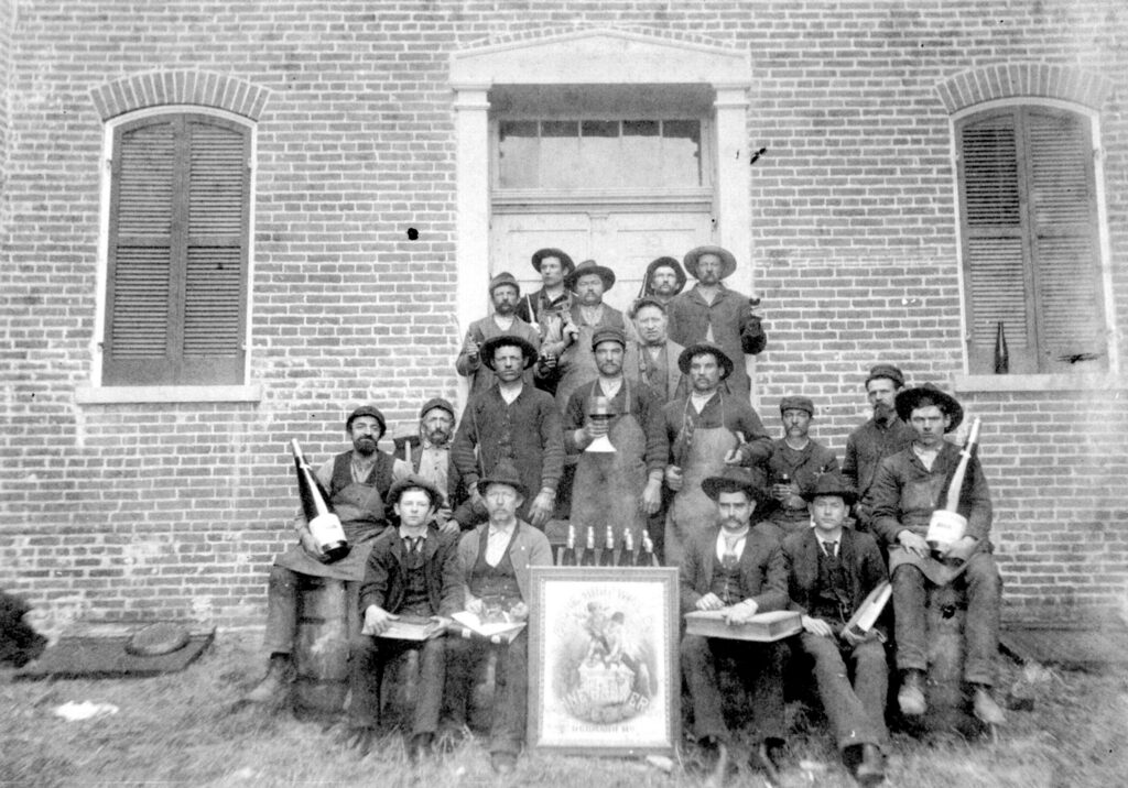 The Stone Hill Winery team gathered outside the winery with a 50th anniversary poster, circa 1897