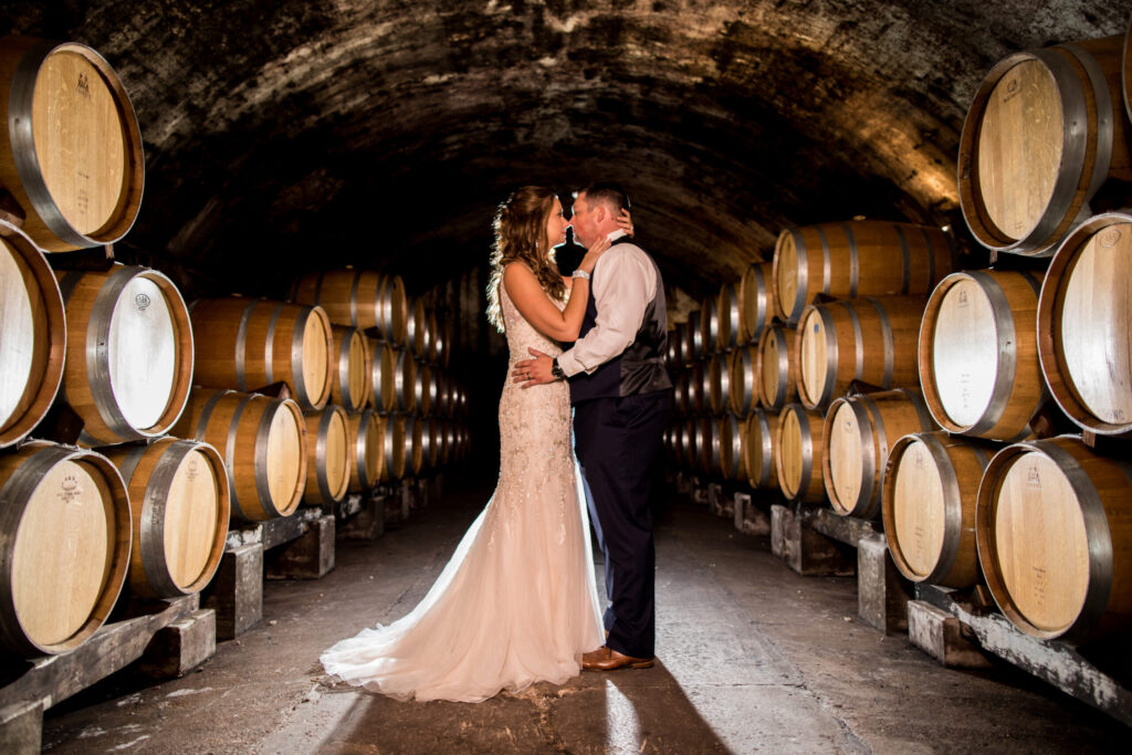 Bride and groom embracing among the oak barrels in the arched underground cellars at Stone Hill