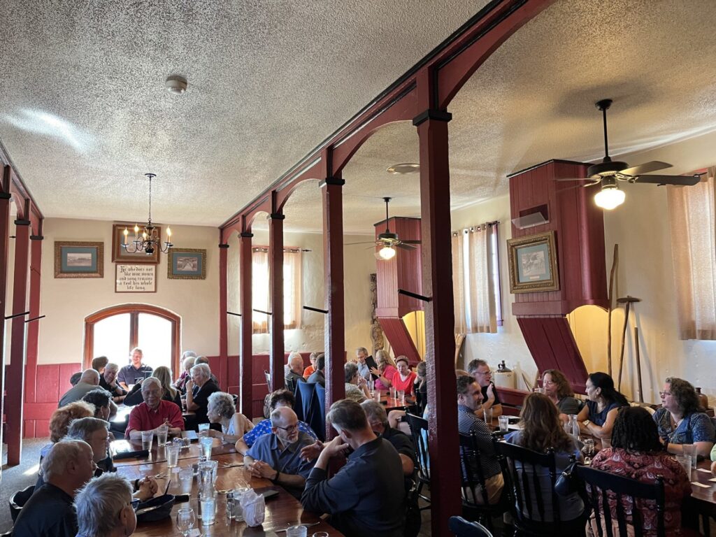 Guests at long tables in the Stables, the main floor of Vintage 1847 Restaurant, under red timber posts and ceiling fans