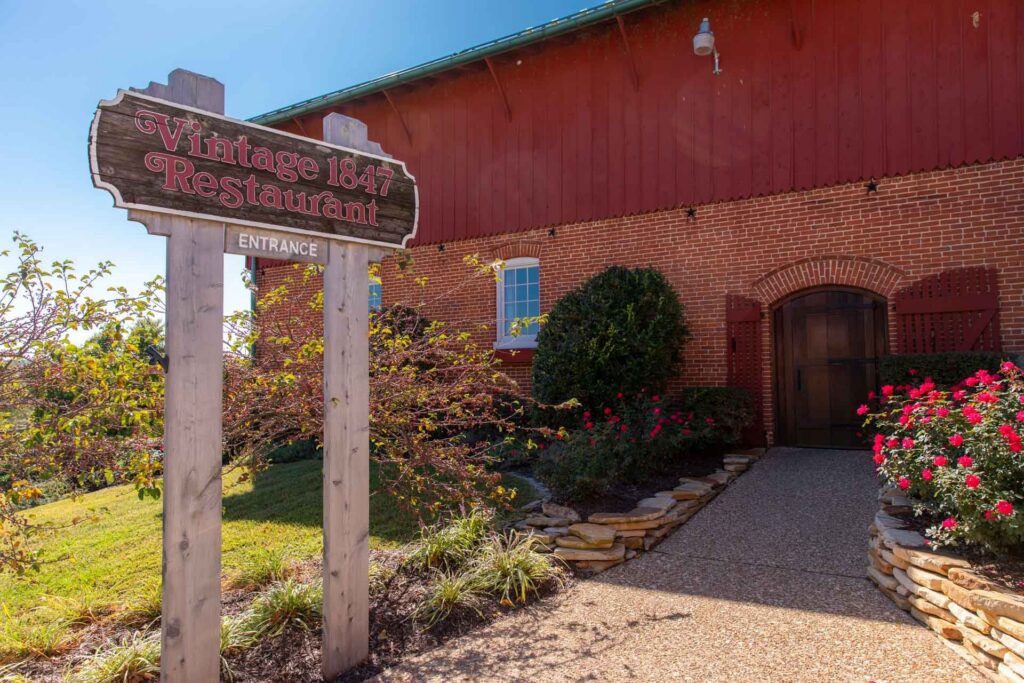 Wooden Vintage 1847 Restaurant sign beside the brick entrance of the restored carriage house and horse barn